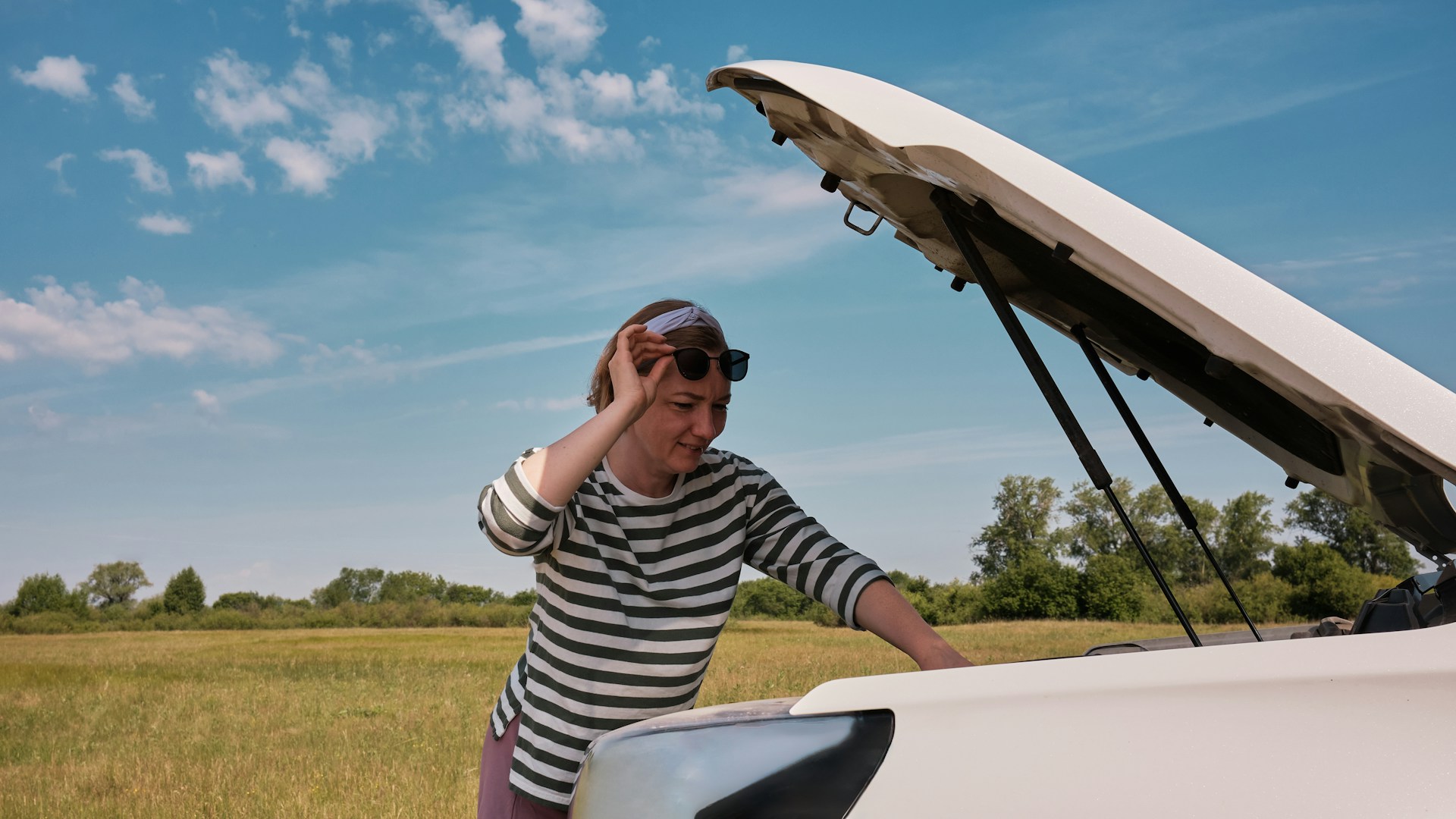 a woman driver near her car with an open hood