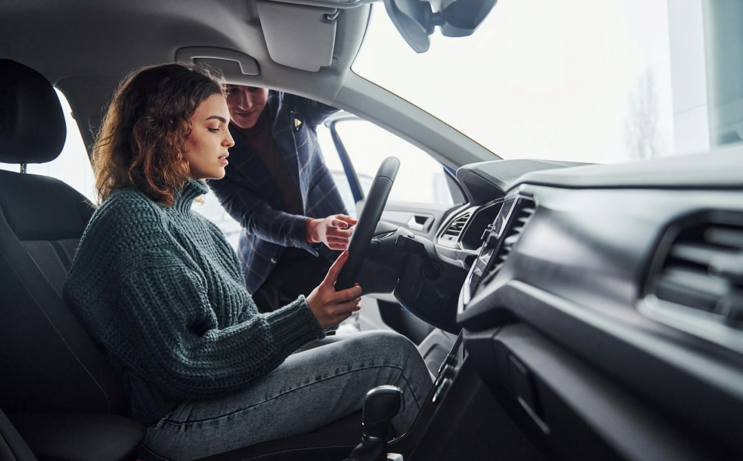 customer sitting in a car while a sales representative explains dashboard features during a dealership visit