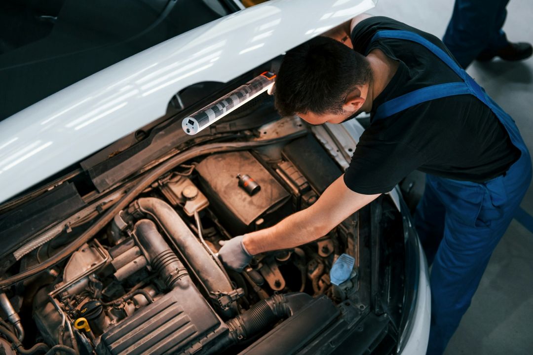 a mechanic is repairing a vehicle engine inside a professional service garage